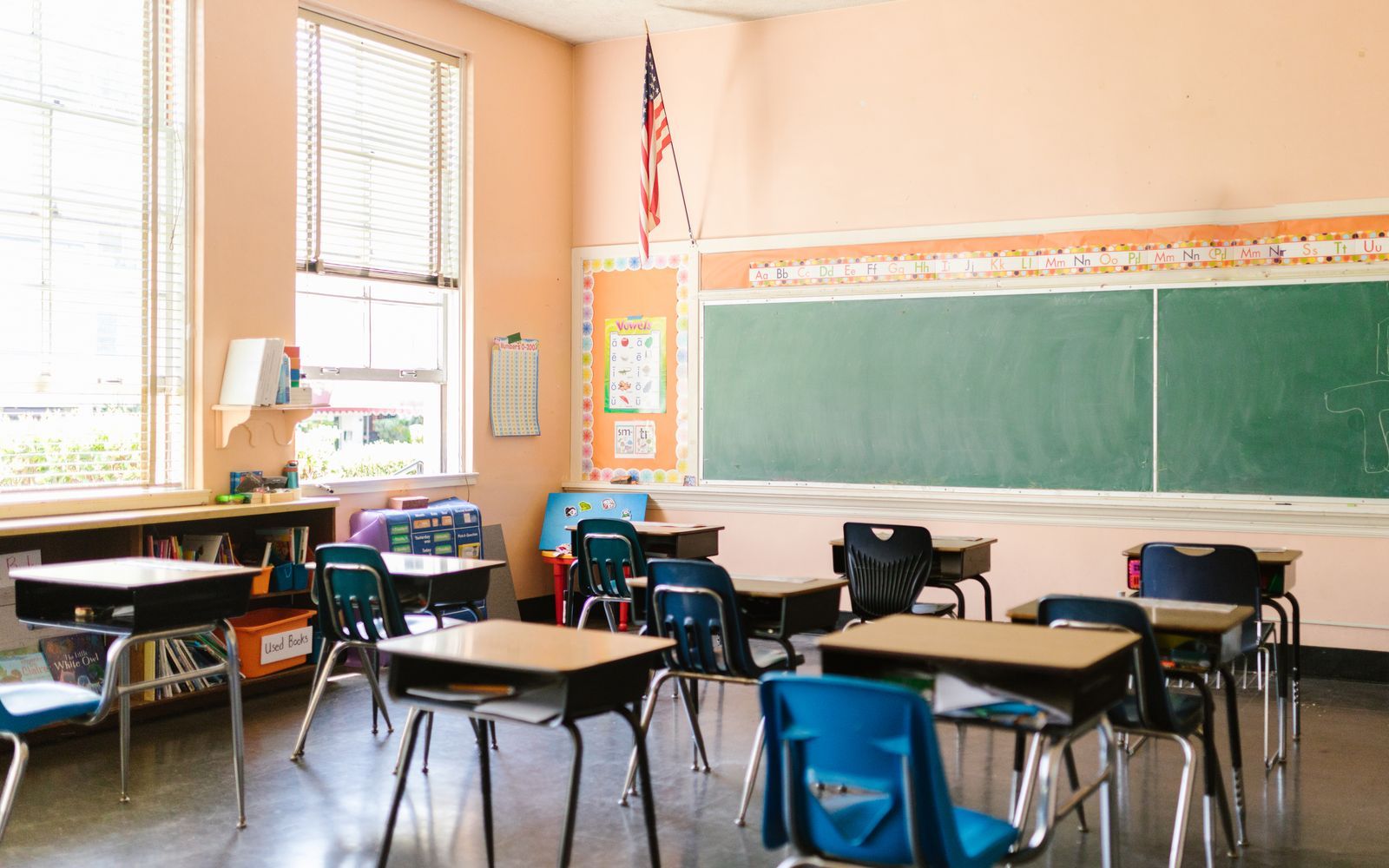 Sunlit classroom with desks arranged and chalkboard at the front
