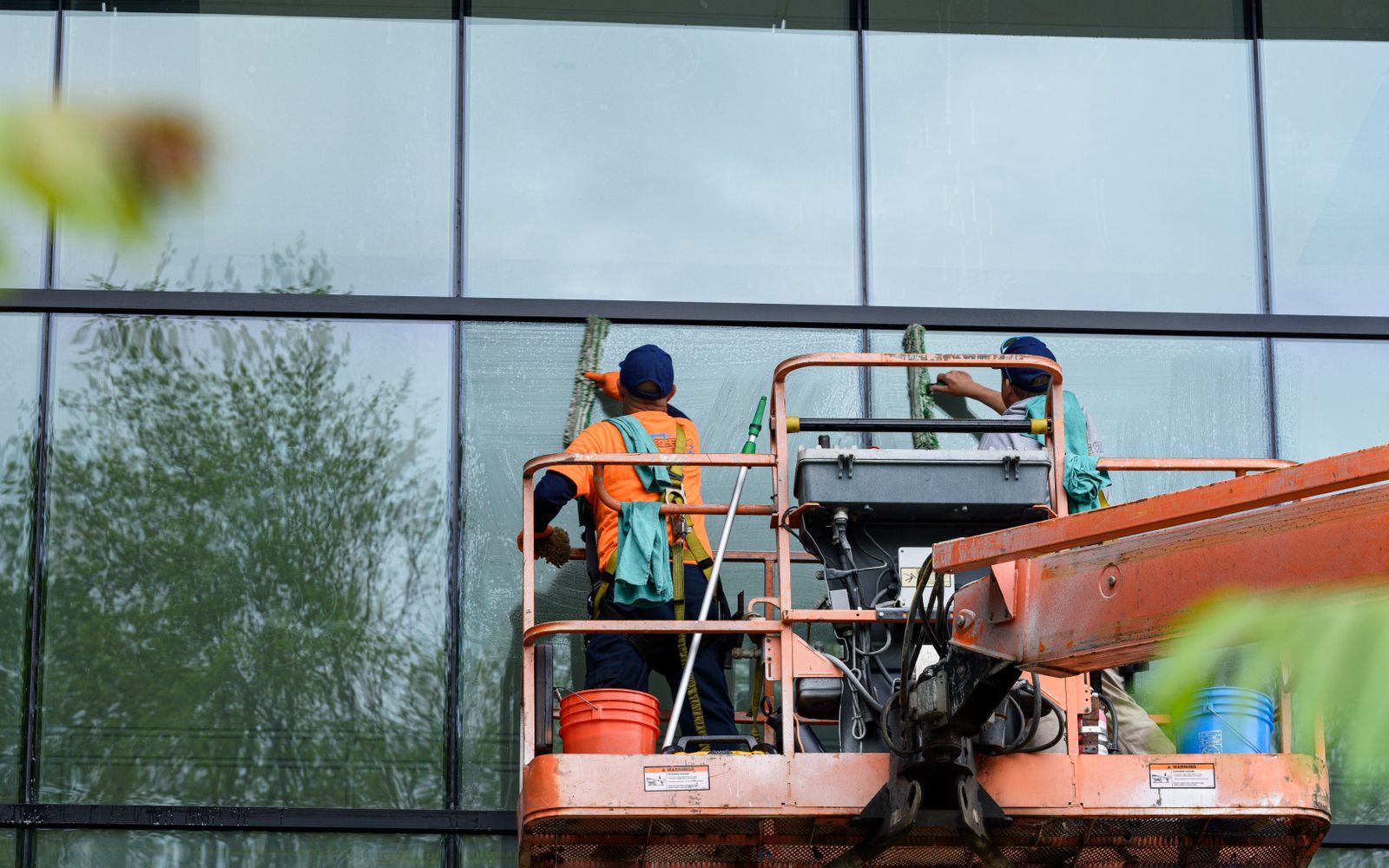 Window cleaning crew working on a commercial building facade from a lift